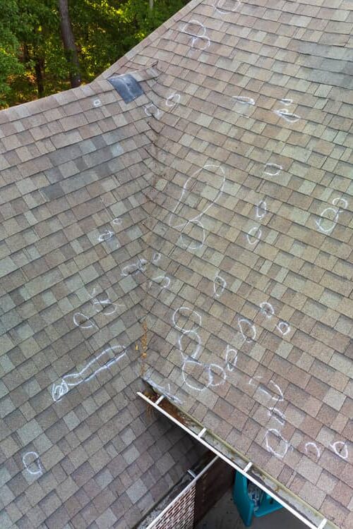 Marked hail damage on a roof by an inspector.