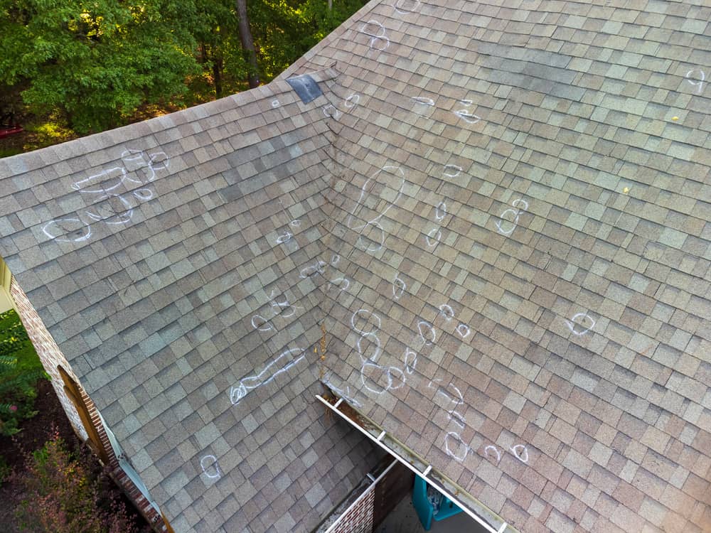 Marked hail damage on a roof by an inspector.