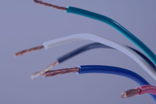 A close-up of multiple colored electrical wires with stripped insulation and exposed copper strands.