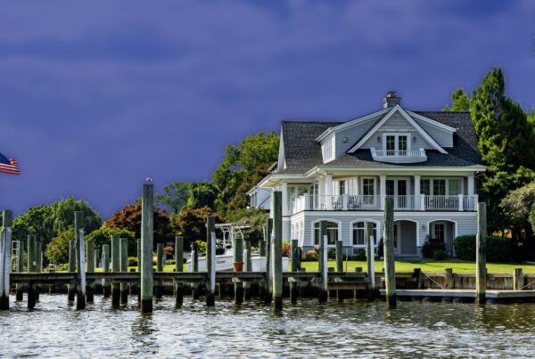 A coastal waterfront home with a wooden boat dock, pilings, and seawall along the water's edge.